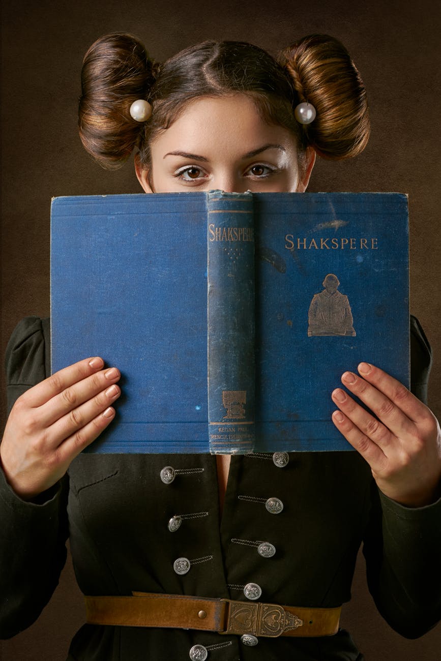 woman holding blue shakspere book over face