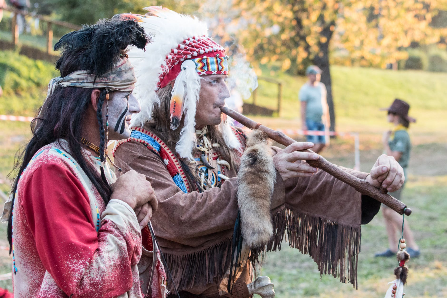 two native american playing wind instrument