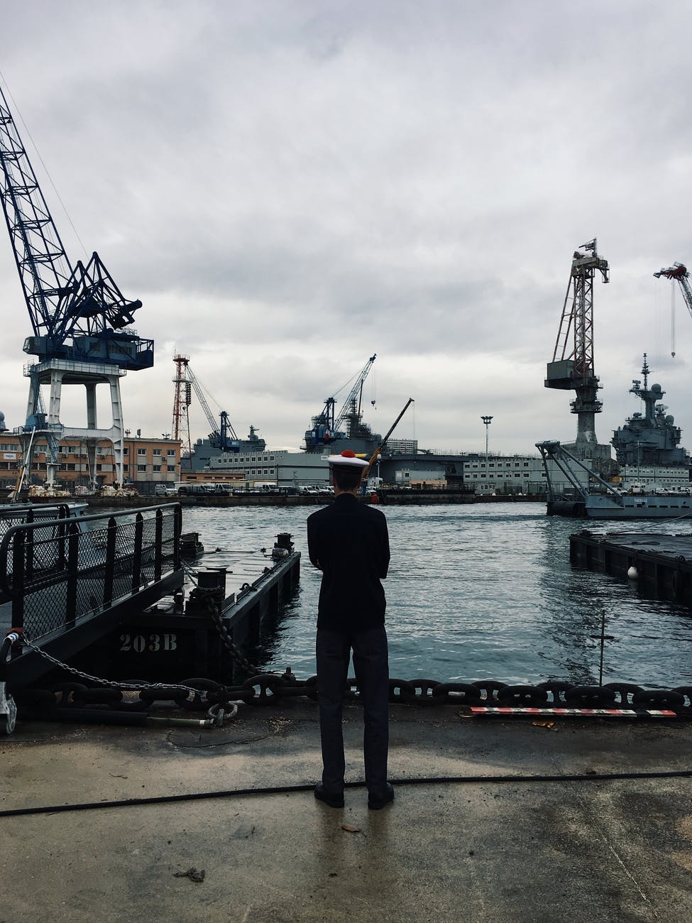 man standing and facing boats on water